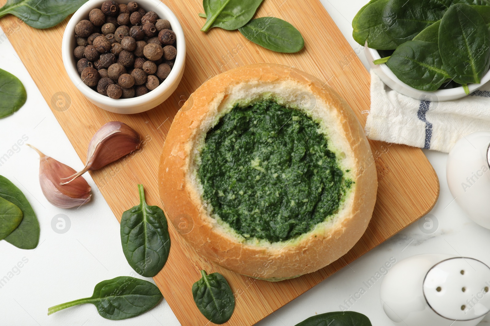 Photo of Delicious spinach sauce in bread bowl on white table, flat lay