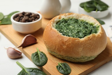 Delicious spinach sauce in bread bowl on white table, closeup