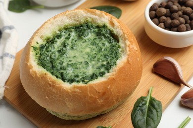 Delicious spinach sauce in bread bowl on white table, closeup