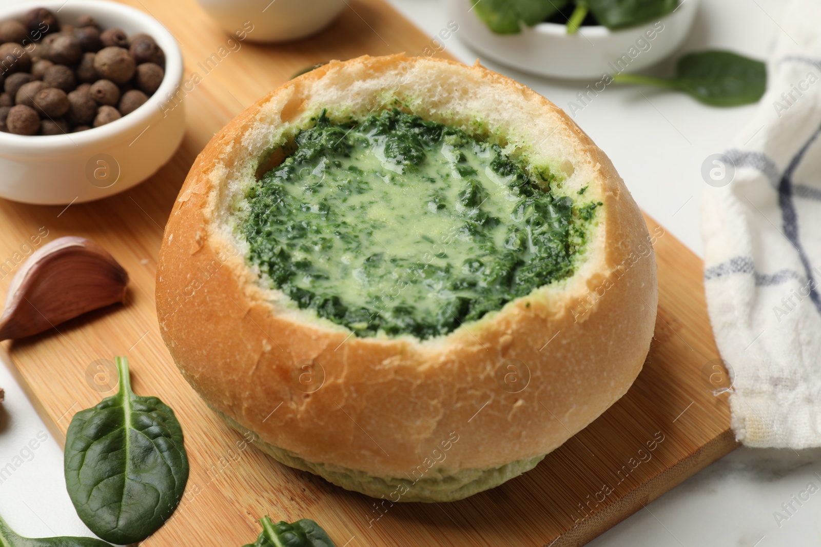 Photo of Delicious spinach sauce in bread bowl on white table, closeup