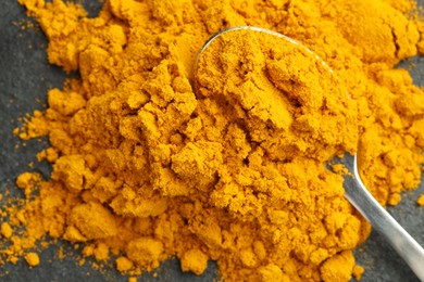 Photo of Turmeric powder and spoon on grey table, top view