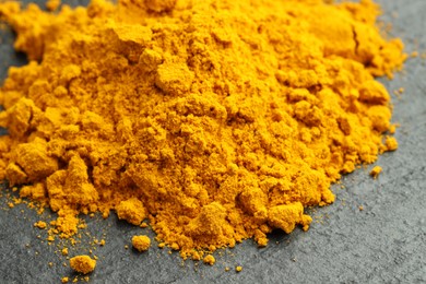 Photo of Heap of turmeric powder on grey table, closeup