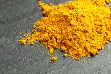 Photo of Heap of turmeric powder on grey table, closeup