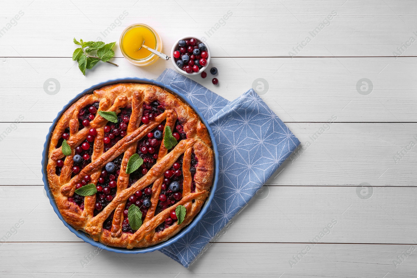 Photo of Delicious currant pie, honey and fresh berries on white wooden table, flat lay. Space for text