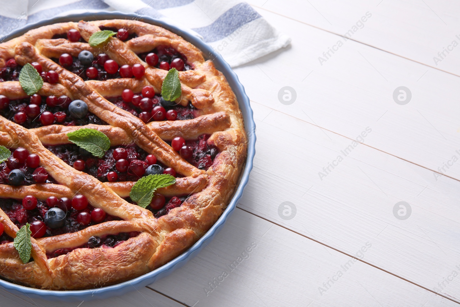 Photo of Delicious currant pie and fresh berries on white wooden table, space for text