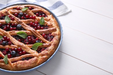 Photo of Delicious currant pie and fresh berries on white wooden table, space for text