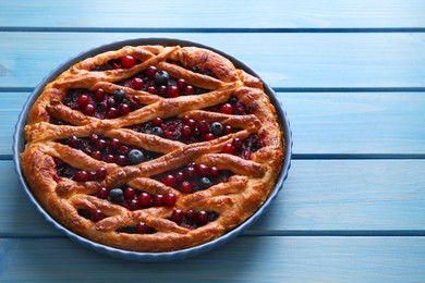 Photo of Delicious currant pie and fresh berries on blue wooden table, space for text