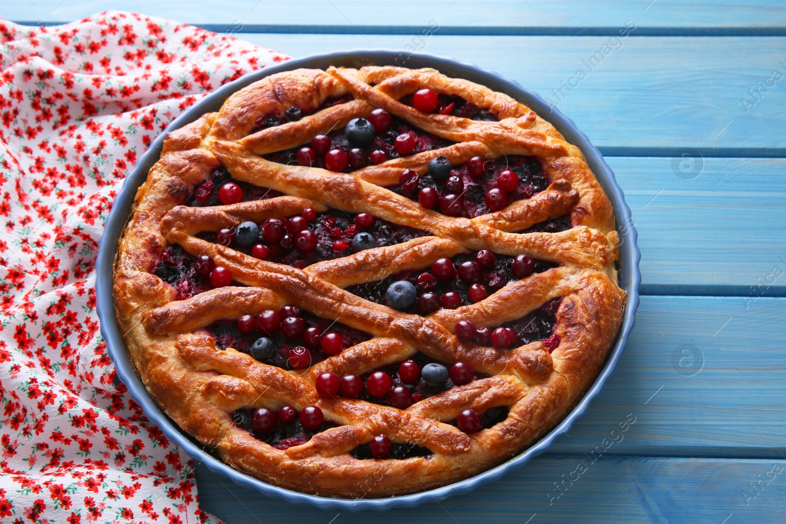 Photo of Delicious currant pie and fresh berries on blue wooden table