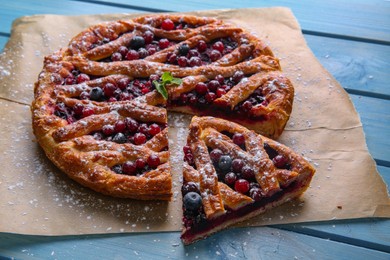 Photo of Delicious cut currant pie and fresh berries on blue wooden table