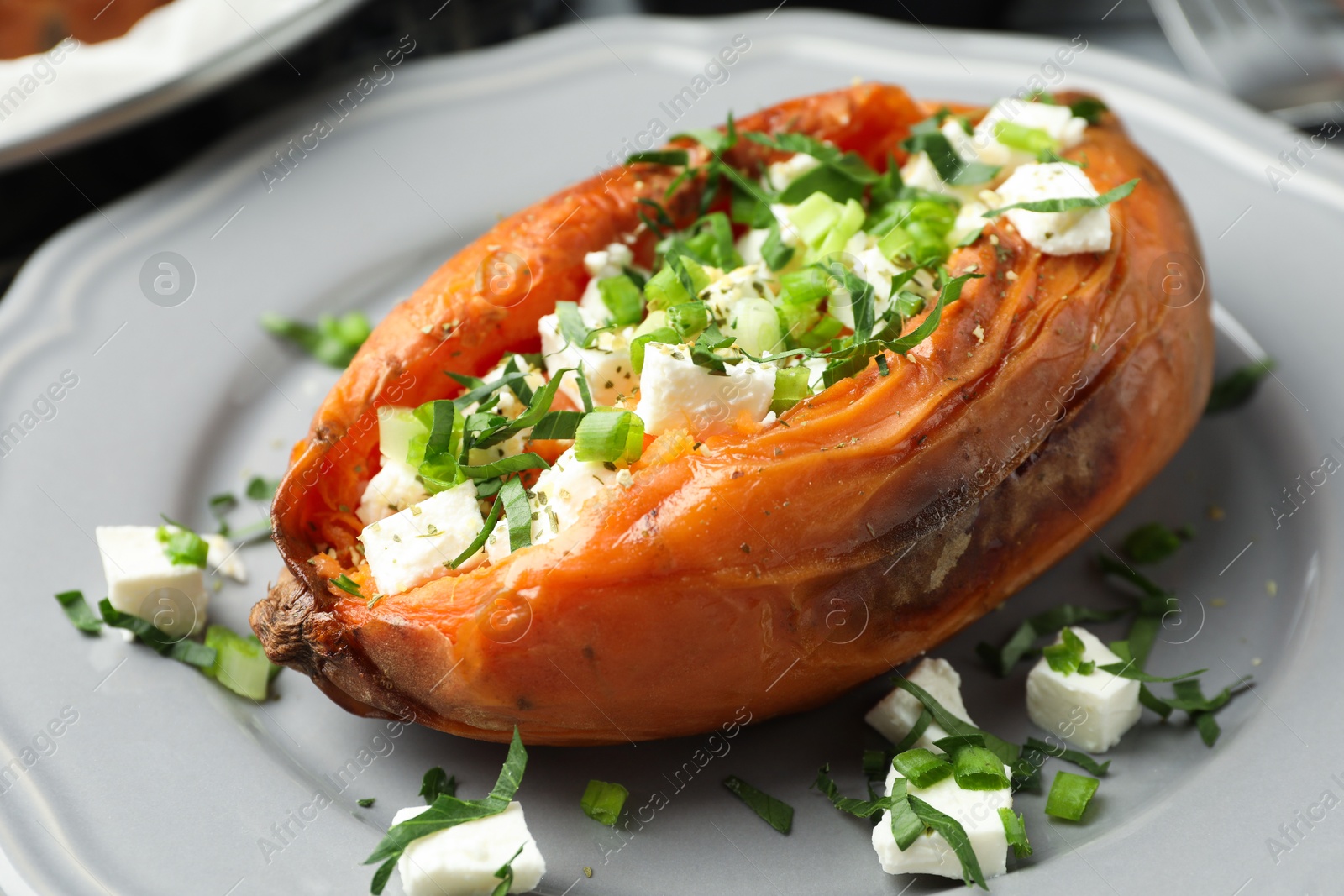 Photo of Tasty cooked sweet potato with feta cheese and green onion on table, closeup