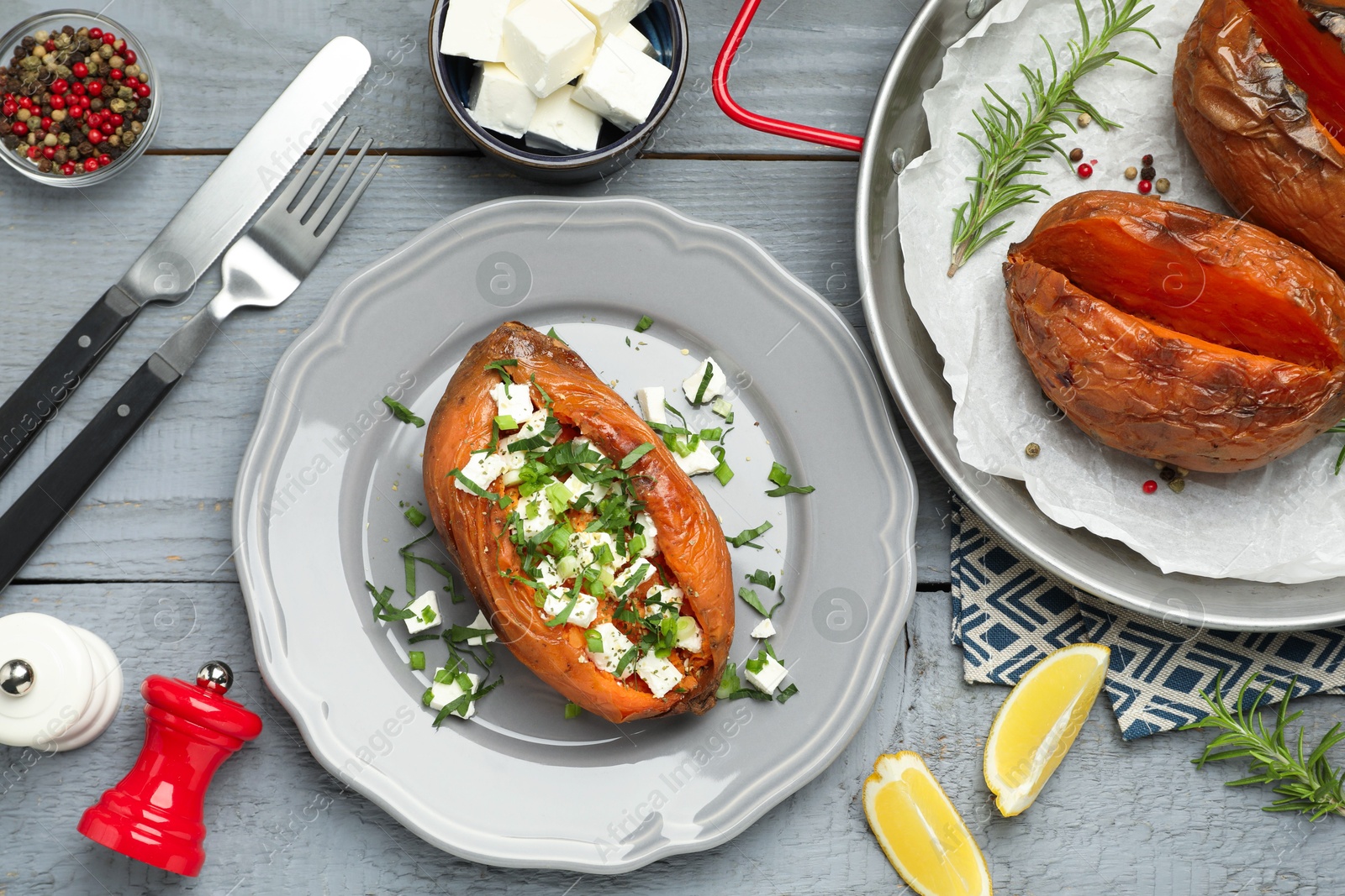 Photo of Tasty cooked sweet potatoes served with feta cheese on grey wooden table, top view