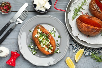 Photo of Tasty cooked sweet potatoes served with feta cheese on grey wooden table, top view