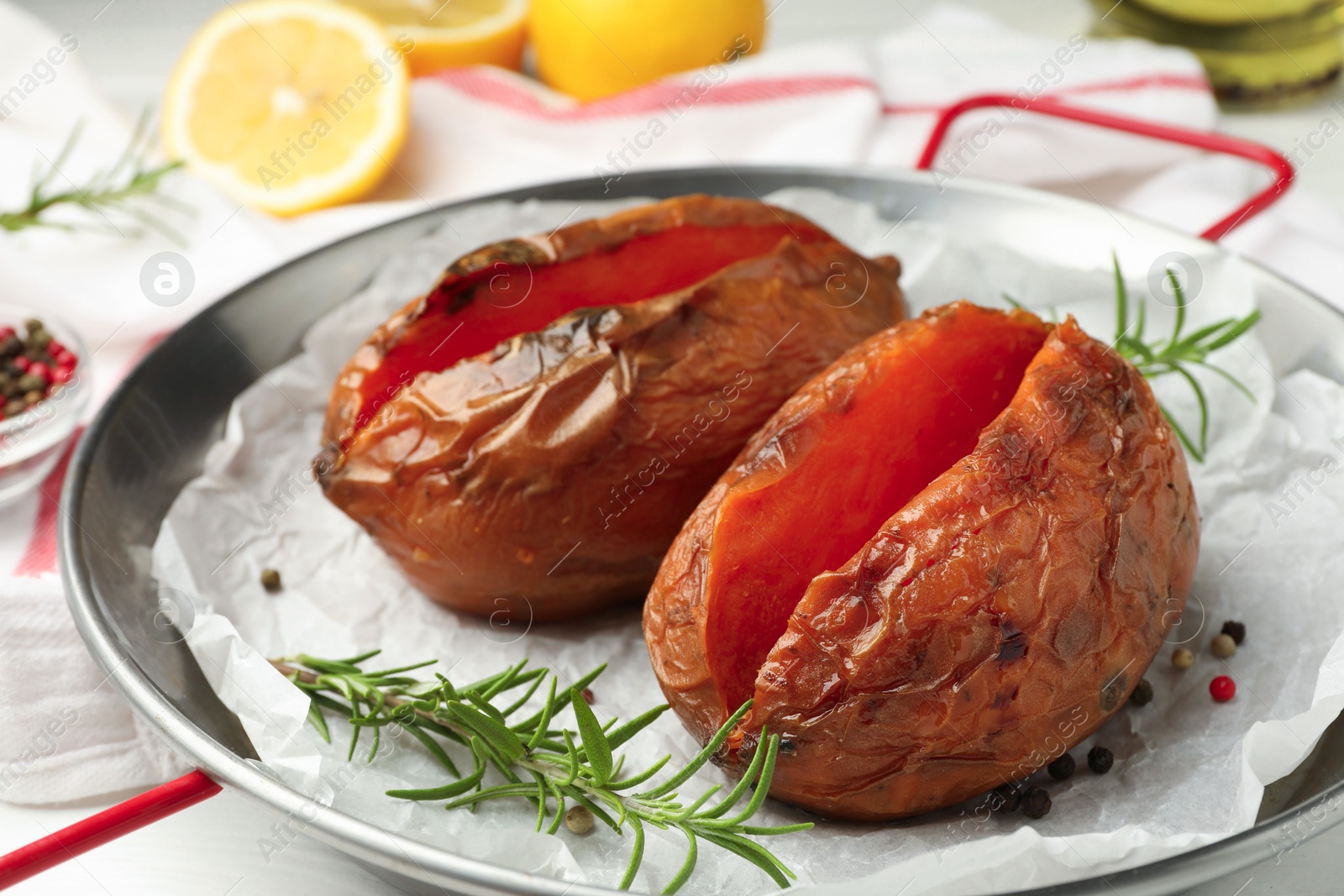 Photo of Tasty cooked sweet potatoes served with rosemary on table, closeup