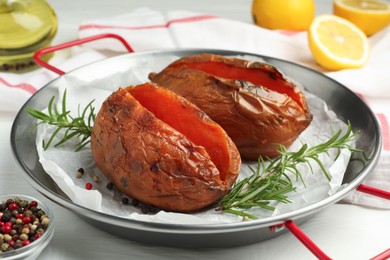 Photo of Tasty cooked sweet potatoes served with rosemary on white table, closeup