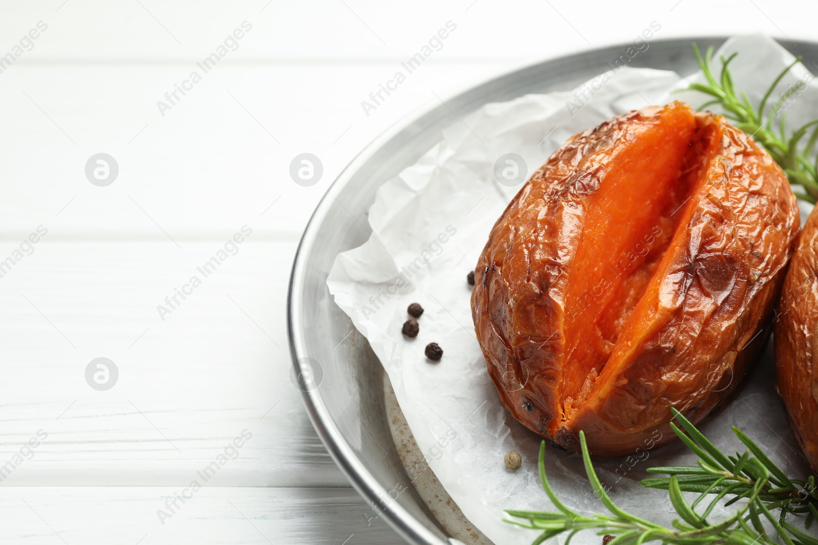 Photo of Tasty cooked sweet potato with rosemary on white wooden table, closeup. Space for text