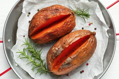 Photo of Tasty cooked sweet potatoes with rosemary on white wooden table, top view