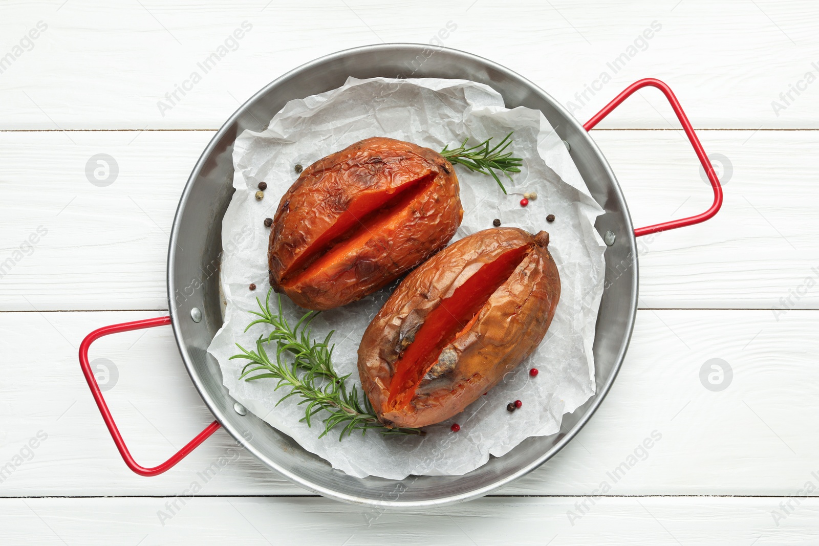 Photo of Tasty cooked sweet potatoes with rosemary on white wooden table, top view