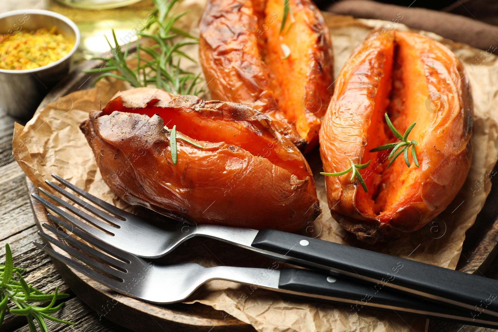 Photo of Tasty cooked sweet potatoes served with rosemary on table, closeup