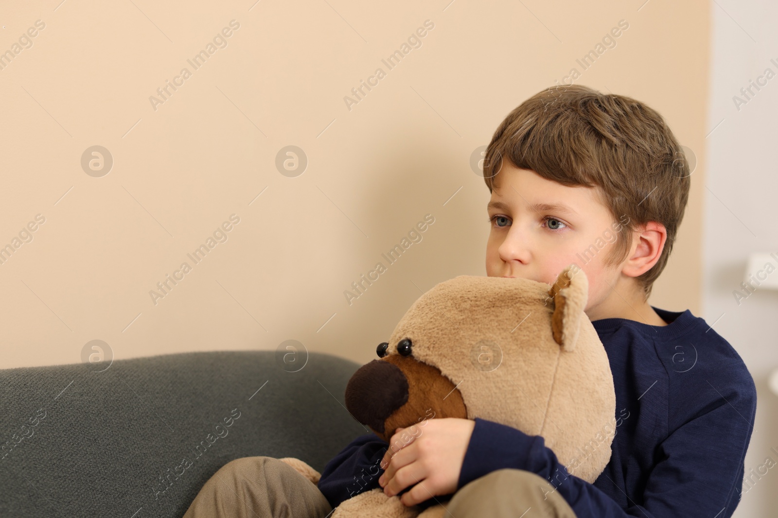 Photo of Autism concept. Lonely little boy with teddy bear on sofa at home