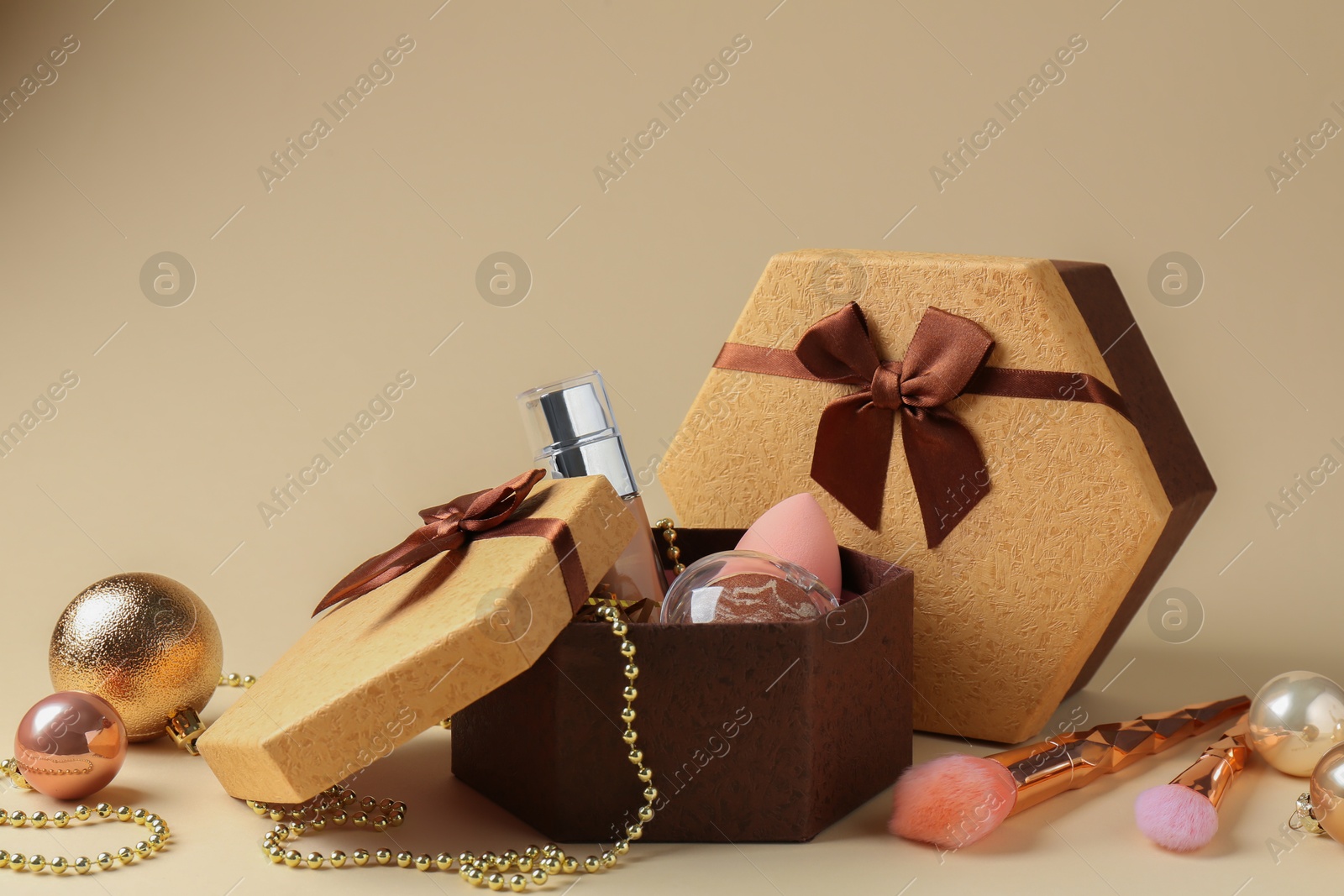 Photo of Cosmetic products as Christmas present. Gift boxes and decor on beige background