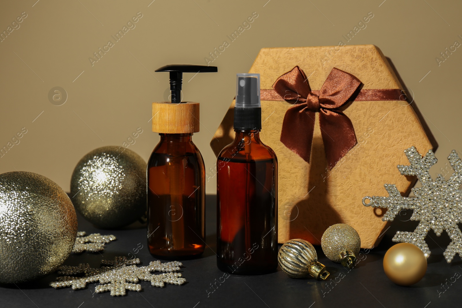 Photo of Cosmetic products as Christmas present, gift box and festive decor on table against dark beige background