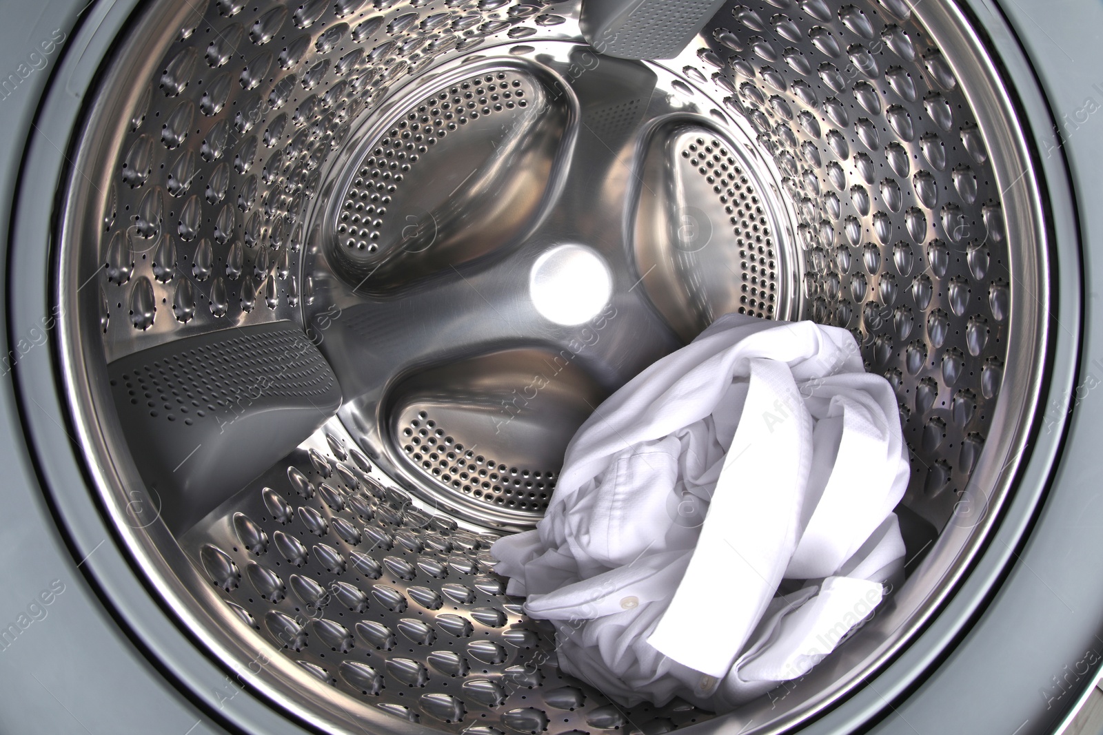 Photo of Washing machine with shirt as background, closeup