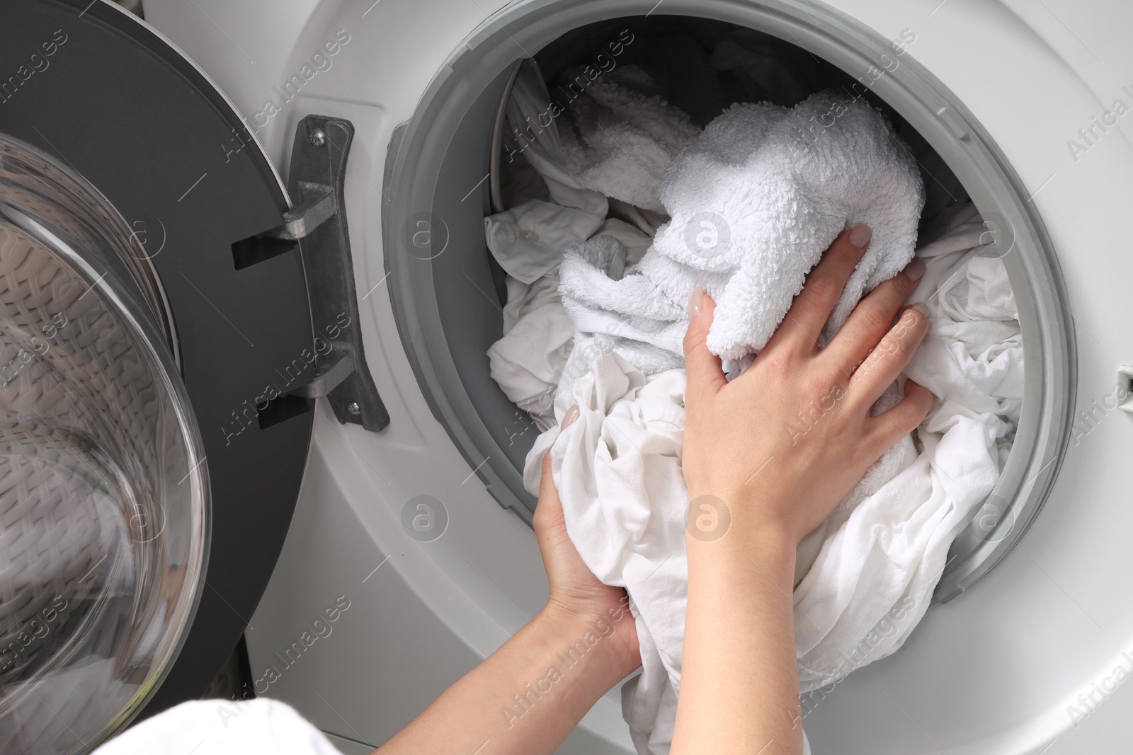 Photo of Woman taking clean clothes out of washing machine, closeup