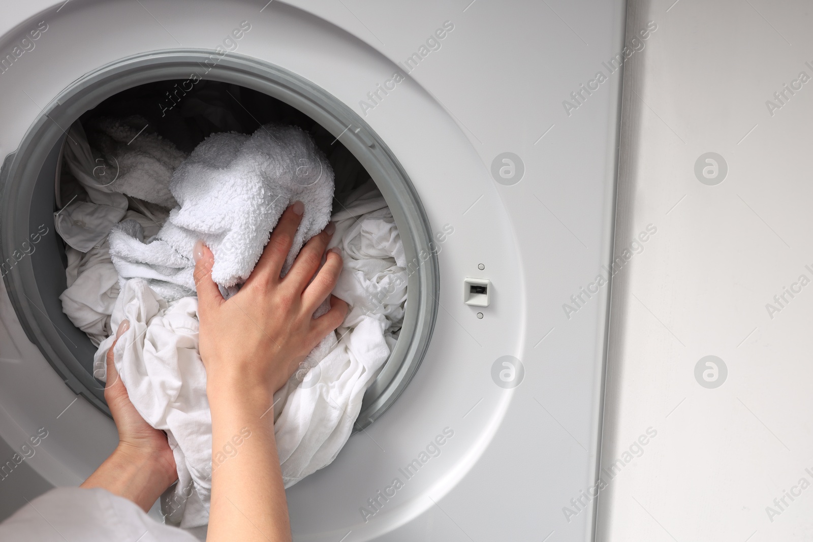 Photo of Woman taking clean clothes out of washing machine, closeup