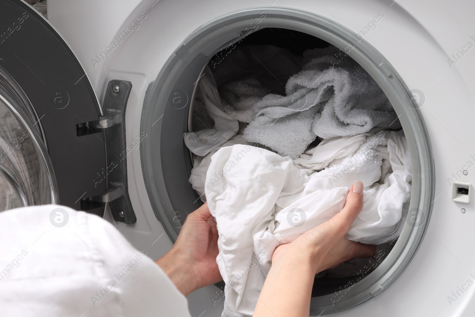 Photo of Woman taking clean clothes out of washing machine, closeup