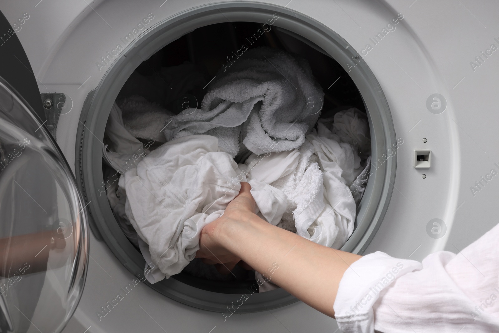 Photo of Woman taking clean clothes out of washing machine, closeup