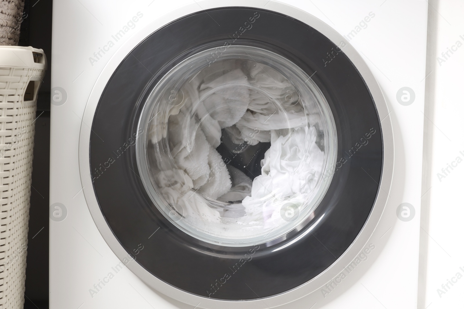 Photo of Washing machine with clothes as background, closeup