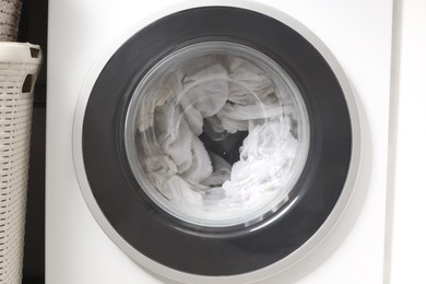 Photo of Washing machine with clothes as background, closeup