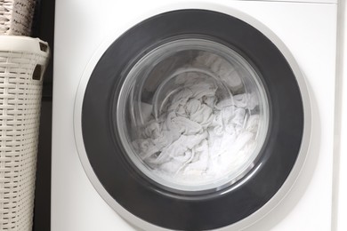 Photo of Washing machine with clothes as background, closeup