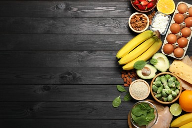 Photo of Different products rich in dopamine on black wooden table, flat lay. Space for text