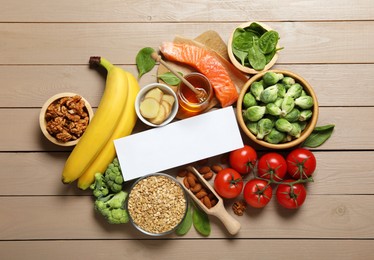 Photo of Word Melatonin and different products on wooden table, flat lay