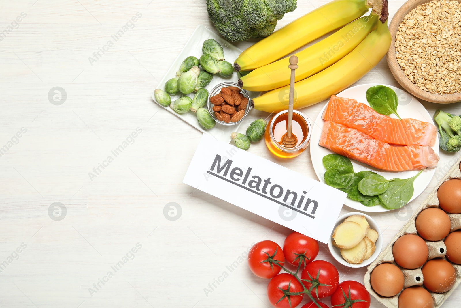 Photo of Word Melatonin and different products on white wooden table, flat lay. Space for text