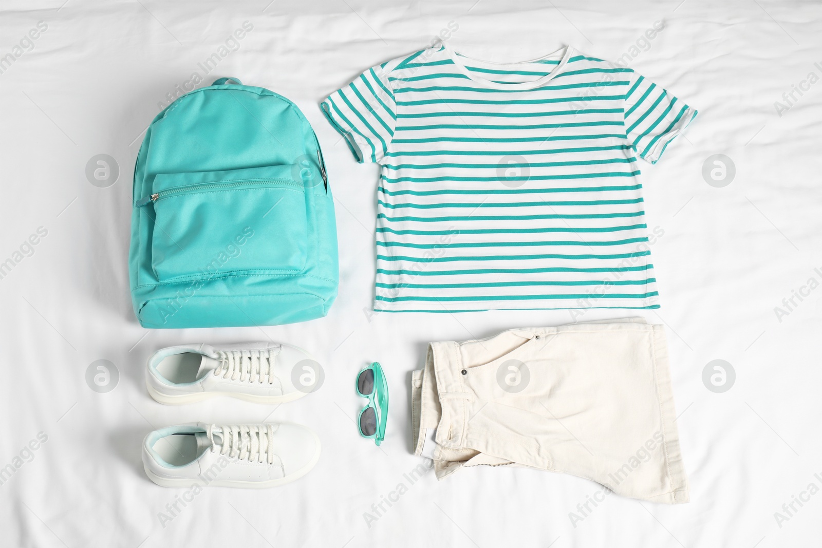 Photo of Stylish outfit with backpack on white fabric, flat lay