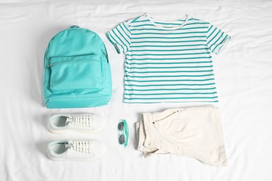 Photo of Stylish outfit with backpack on white fabric, flat lay