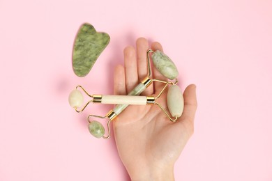 Photo of Woman with face rollers and gua sha tool on pink background, top view