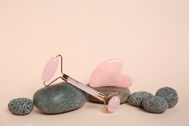 Photo of Face roller, gua sha tool and stones on beige background