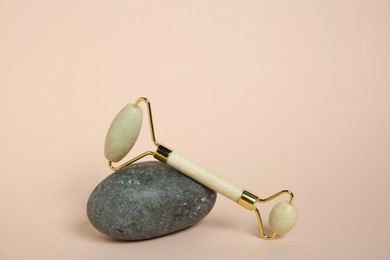 Photo of Face roller and stone on beige background