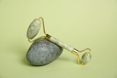 Face roller and stone on light green background