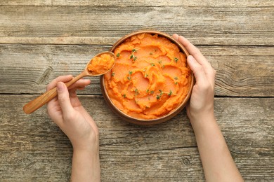 Photo of Woman eating tasty mashed sweet potato at wooden table, top view