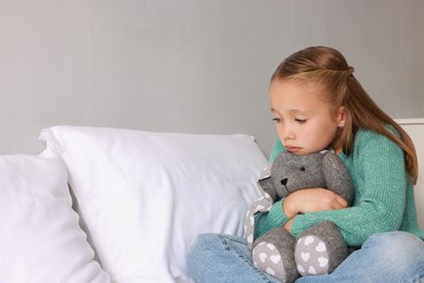 Photo of Autism concept. Lonely little girl with toy bunny on bed at home