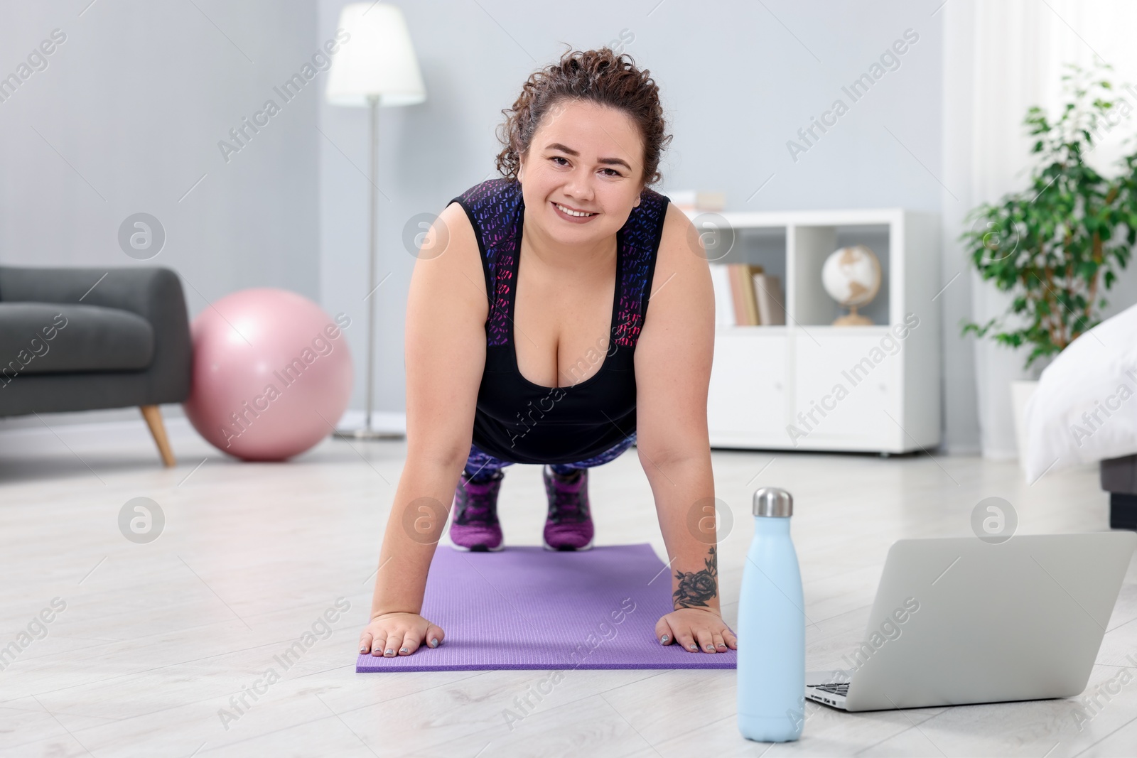 Photo of Plus size woman having fitness training with online coach via laptop at home