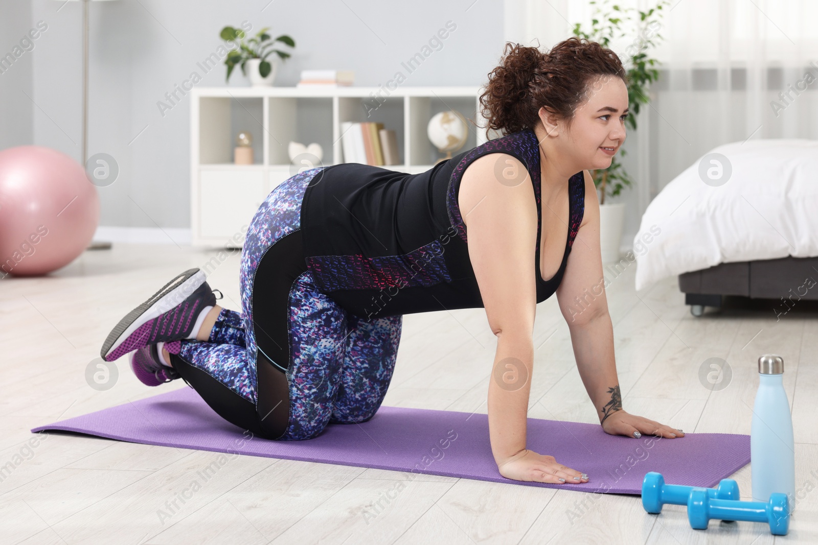 Photo of Plus size woman exercising on fitness mat at home