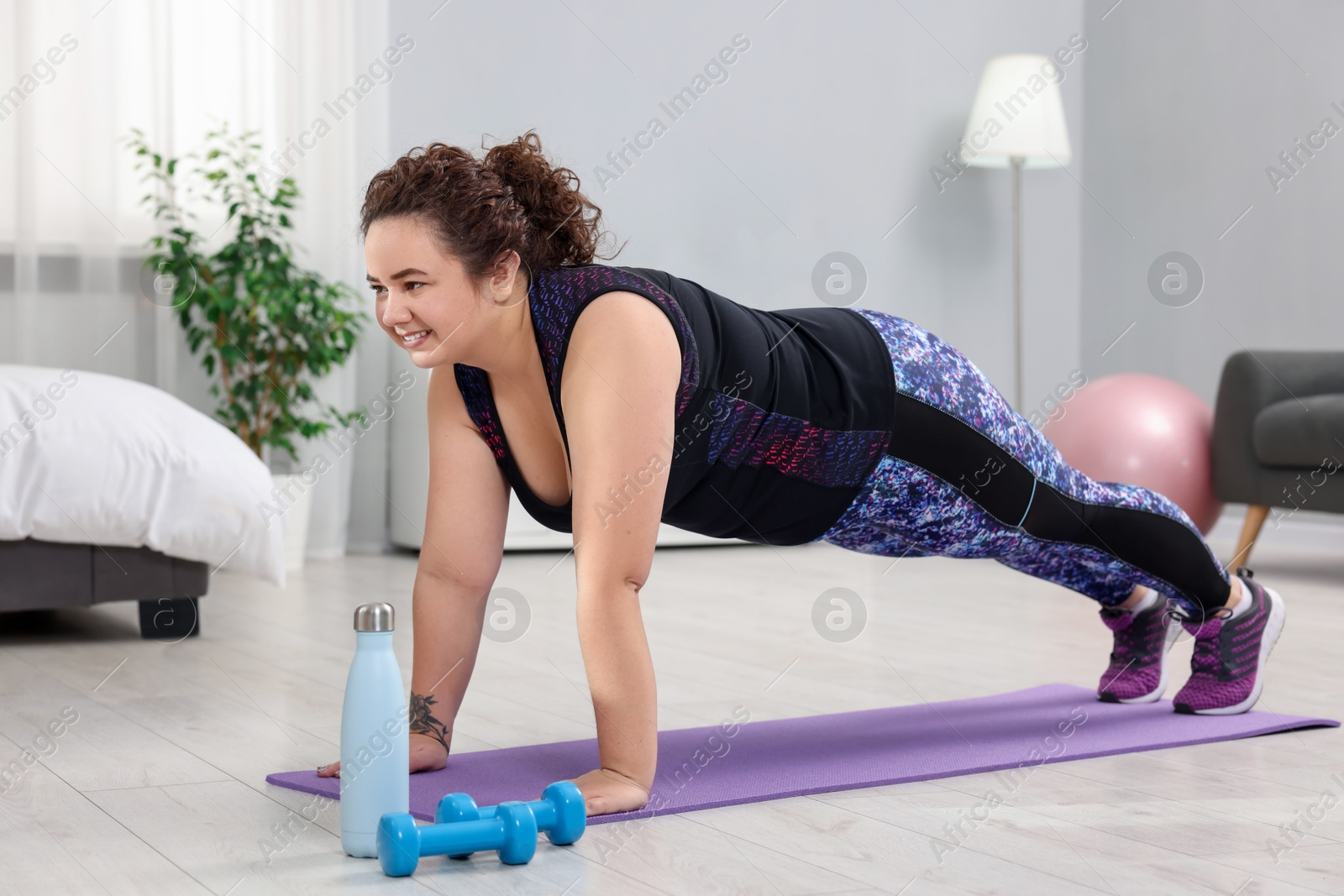 Photo of Woman doing plank exercise on fitness mat at home