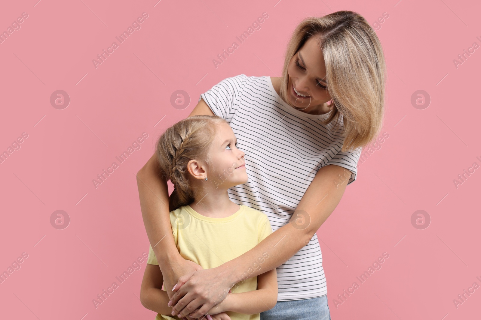 Photo of Cute little girl with her mom on pink background. Happy Mother's Day