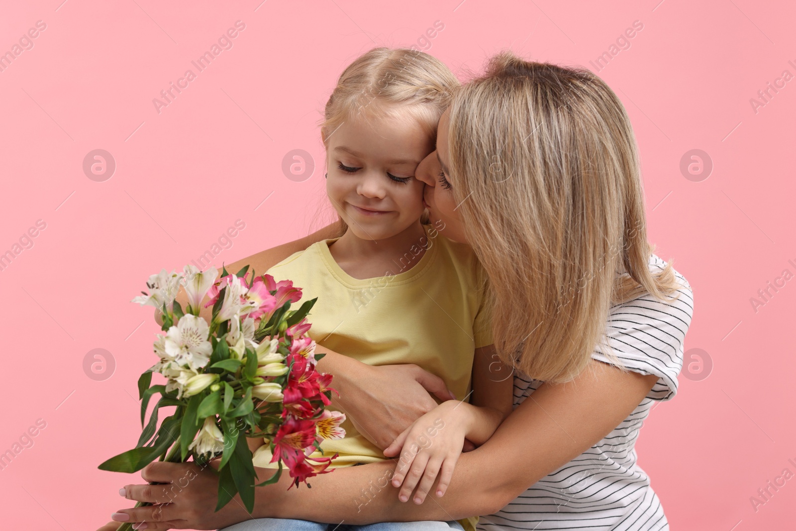 Photo of Little daughter congratulating her mom with bouquet of alstroemeria flowers on pink background. Happy Mother's Day