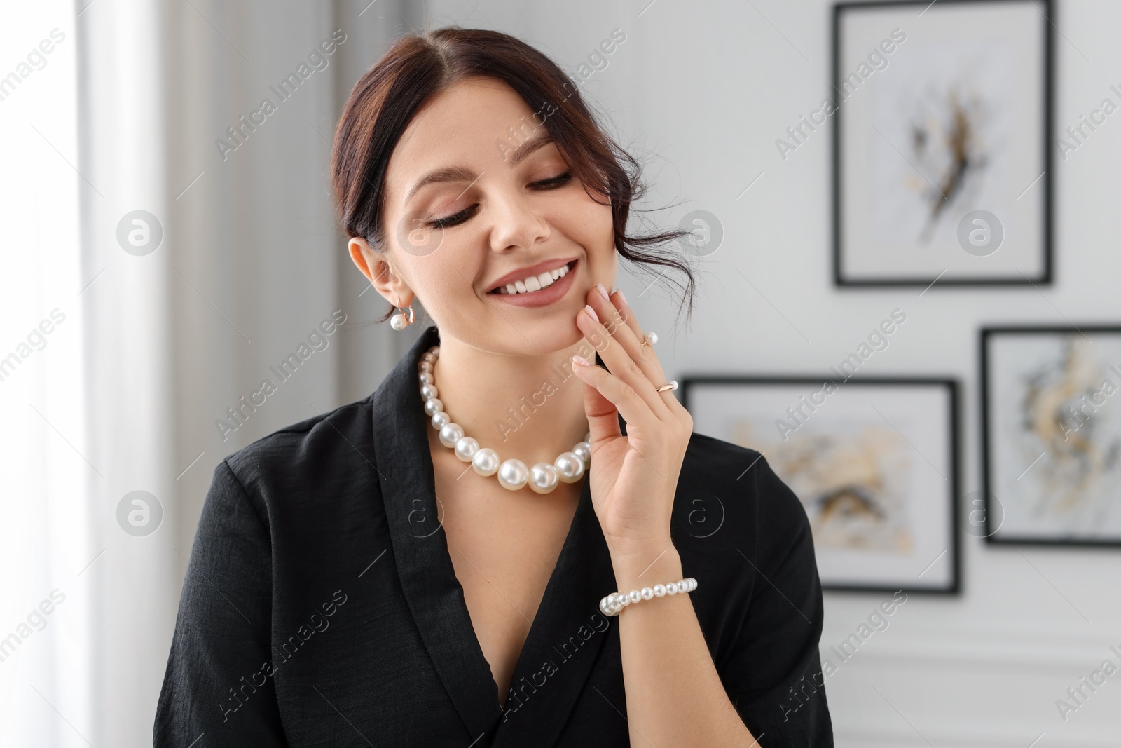 Photo of Beautiful young woman wearing elegant pearl jewelry indoors